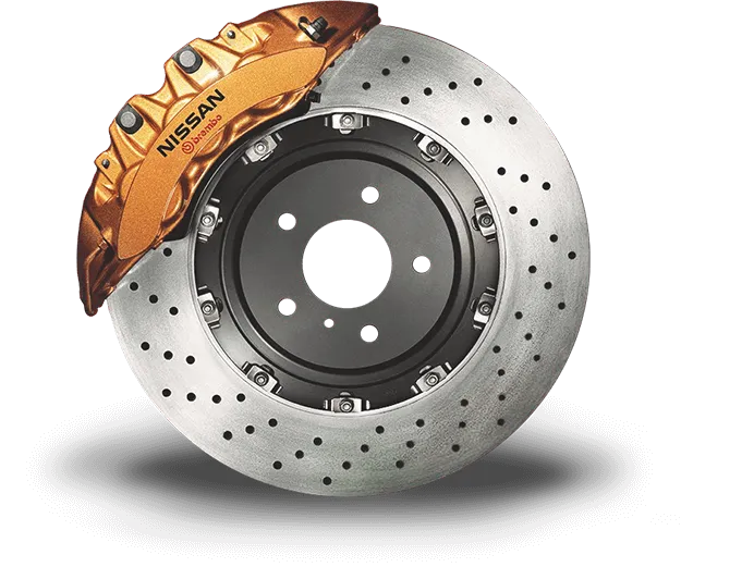 Close-up of a Nissan brake caliper in orange on a perforated brake disk, showcasing high-performance automotive components.