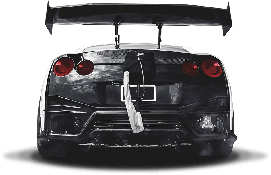 Rear view of a sleek black sports car with a prominent rear wing and red tail lights, showcasing a high-performance appearance modigied by T1 Race Development